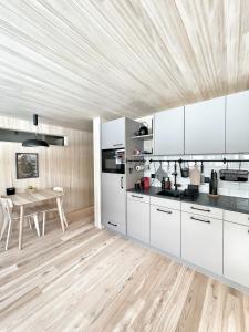 a kitchen with white cabinets and a wooden floor at Nanisgarten - Grannys flat in Obergesteln