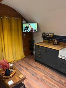 een keuken met een tv aan de muur en een tafel bij Portside Pasture - (Luxury Cabin) in Portpatrick