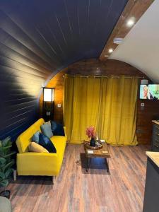 a living room with a yellow couch and a table at Portside Pasture - (Luxury Cabin) in Portpatrick