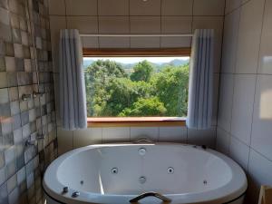 a bath tub in a bathroom with a window at Chalés Cantinho do Céu in Monte Verde