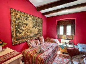 Habitación roja con cama y pintura en la pared en La Morada Del Unicornio, en Calonge