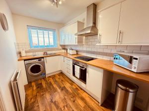 a kitchen with white cabinets and a washer and dryer at Spanish City View 2, Luxury Sea Front Apartment Free Onsite Parking in Whitley Bay