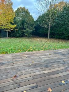 a wooden deck with leaves on the ground in a park at Maison individuelle prVersailles in Villennes-sur-Seine +3 photos