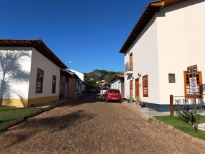 a red car parked on a dirt road between buildings at Casa Tanure in Pirenópolis