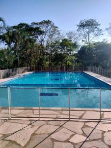 a large blue swimming pool with trees in the background at Casa Tanure in Pirenópolis