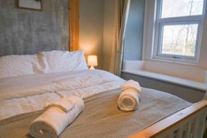 a bed with towels on it with a window at Hycemoorside House in Millom
