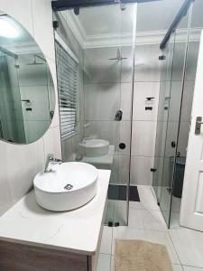 a white bathroom with a sink and a shower at Sunny Side Apartment in Knysna