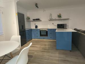 cocina con armarios azules, mesa y sillas en Sunny Side Apartment, en Knysna