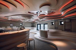 a bar in a restaurant with wooden ceilings and stools at Villa Viva - ein Haus das Brunnen baut in Hamburg