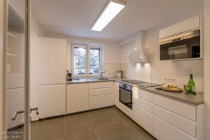 a white kitchen with white cabinets and a window at Ferienhaus Taubenhof in Simprechtshausen