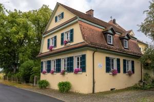 ein gelbes Haus mit Blumen an den Fenstern in der Unterkunft Alte Schule in Herrentierbach