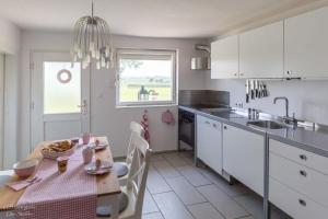 uma cozinha com uma mesa e uma cozinha com armários brancos em Ferienhaus S`bunde Heisle em Blaufelden