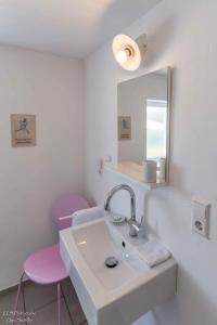 a bathroom with a sink and two pink chairs at Ferienhaus S`bunde Heisle in Blaufelden