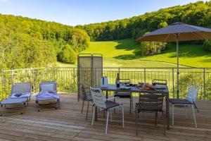 un tavolo con sedie e un ombrellone su una terrazza di Freistehendes Ferienhaus mit Kamin, Sauna, atemberaubenden Blick ins Tal, mehrere Terrassen, 1500qm Grundstück 1,6m hoch eingezäunt a Gerabronn