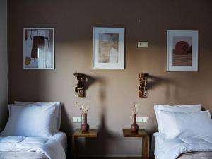 dwa łóżka w pokoju z obrazami na ścianie w obiekcie vaya_living w mieście Ktistádes
