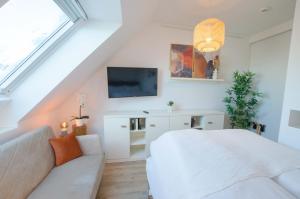 um quarto com uma cama branca e um sofá em Gemütliches Apartment im Zentrum em Augsburg
