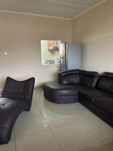 a living room with a black leather couch and a refrigerator at Gardenlea in Durban