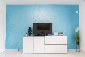 a television on a white cabinet in a room with a blue wall at Maris in Osijek
