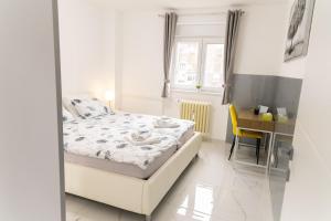 a white bedroom with a bed and a desk at Maris in Osijek