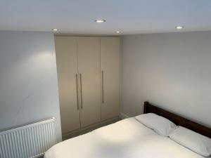a bedroom with white cabinets and a bed at Cosy spacious master room. in London