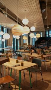 un restaurant avec des tables en bois, des chaises et des lumières dans l'établissement Villa Viva Hamburg, à Hambourg