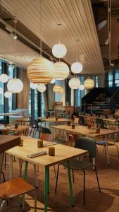 a restaurant with wooden tables and chairs and lights at Villa Viva - ein Haus das Brunnen baut in Hamburg