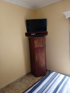1 dormitorio con TV de pantalla plana en un armario de madera en Logement Petit Studio Salazamay Tamatave Madagascar, en Toamasina