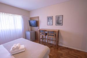 um quarto de hotel com uma cama, uma mesa e uma televisão em El Misti Coliving Obelisco em Buenos Aires