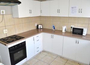 a kitchen with white cabinets and a stove and a microwave at HOME AWAY FROM HOME in Cape Town