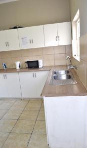 a kitchen with white cabinets and a sink at HOME AWAY FROM HOME in Cape Town +5 photos