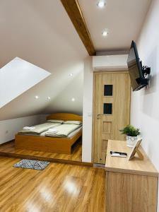 a bedroom with a bed and a desk with a television at Pietro Pokoje B&B Czarna in Czarna