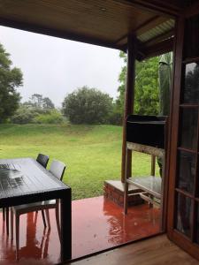 a porch with a table and chairs and a view of a field at Acorn Log Home in Port Elizabeth