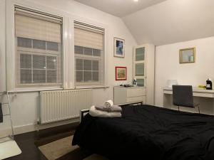 een slaapkamer met een bed, een bureau en 2 ramen bij Luxury Cottage Room in Londen