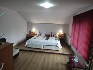 sypialnia z białym łóżkiem i czerwonymi zasłonami w obiekcie Guest House Lila w mieście Bansko