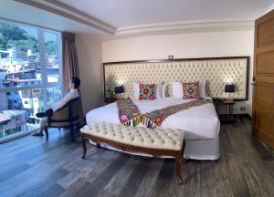una camera con un grande letto e una donna seduta su una sedia di Jaya Machu Picchu Boutique Hotel a Machu Picchu
