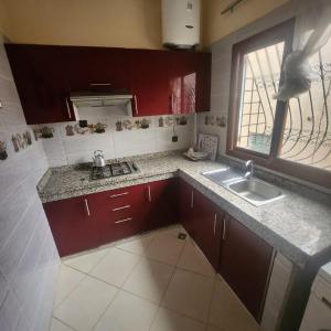 uma cozinha com armários vermelhos, um lavatório e uma janela em B 1 apartment em Fez