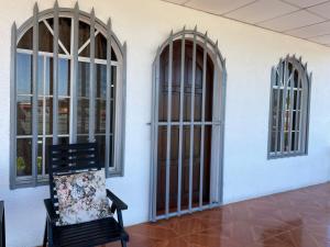 a black chair in a room with three windows at Casa Robles - Your Stay Near Airport in Managua