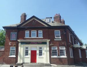 een oud bakstenen gebouw met een rode deur bij The Cabbage Hall Hotel in Liverpool