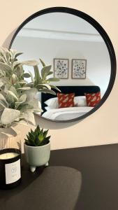 a mirror in a bedroom with a bed and a plant at Superb & Stylish - Free Parking - Gated Community in Hatfield