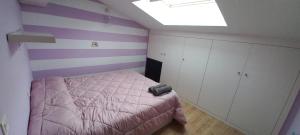 a bedroom with a pink bed and purple stripes at Espectacular Ático con garaje a 10 minutos de Valladolid in Valladolid