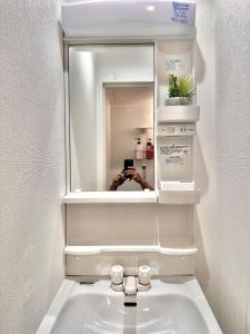 una persona que toma una foto de un espejo sobre un fregadero en totoro no tema room - Vacation STAY 15797 en Osaka