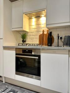 cocina con armarios blancos y horno en Superb & Stylish - Gated Community - Free Parking en Hatfield