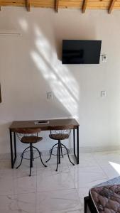 ein Tisch mit zwei Stühlen und ein Fernseher an einer Wand in der Unterkunft Eco Chalés Pedra Bela in Pedra Bela