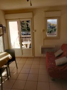 sala de estar con sofá y 2 ventanas en Appartement, en Lamalou-les-Bains