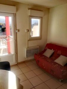 a red couch in a room with a window at Appartement in Lamalou-les-Bains