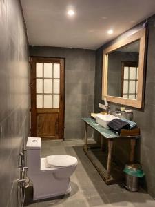 a bathroom with a toilet and a sink and a mirror at Mandaal Corbett in Rāmnagar