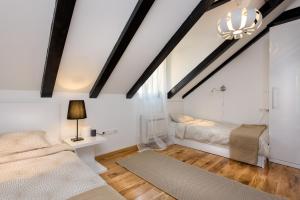 une chambre mansardée avec deux lits et un lustre dans l'établissement Humac Infinity Vero Apartments, à Donji Humac 16 autres photos