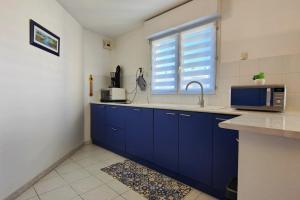 uma cozinha com armários azuis, um micro-ondas e uma janela em Lovely spacious nest in Port Fréjus em Fréjus
