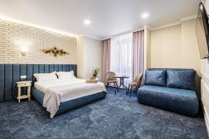 Habitación de hotel con cama y sofá azul en ApartReserve Avtorskiy, en Ivano-Frankivsk