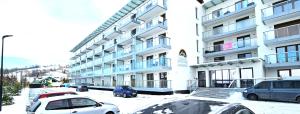 un gran edificio blanco con coches aparcados en la nieve en VIP Apartamenty Zakopianskie, en Zakopane 102 fotos más